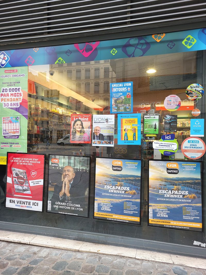 Quatre affiches encadrées alignées dans la vitrine d’un point presse