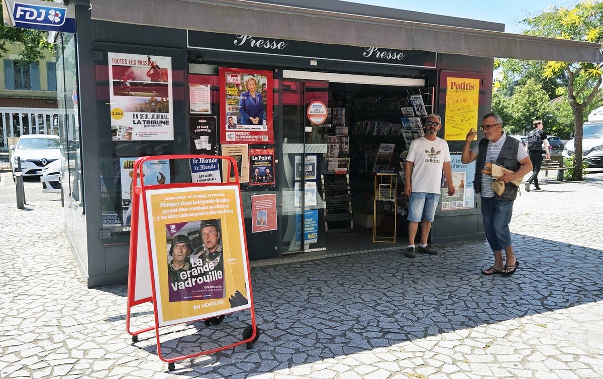 Kiosque à journaux : affiches en façade et chevalet sur le trottoir